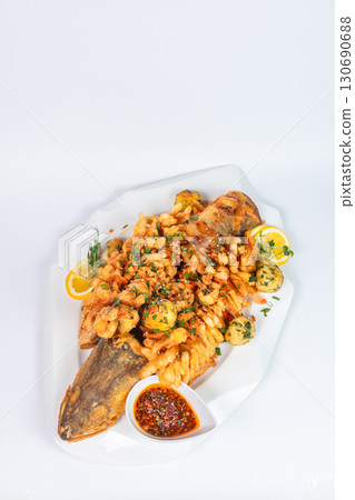 Tasty fried fish served with golden potatoes and creamy sauce on white background. 130690688