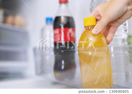 A person taking juice out of the refrigerator 130690805