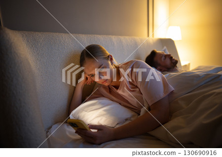 Tired woman awake absorbed in social media in phone, insomnia worsens, digital addicton, cheating 130690916