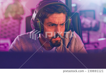 Serious video game, man and esports to play online games, virtual competition and face in dark room. Gamer guy, gaming and night on headset in neon lighting, technology and digital computer streamer Serious video game, man and esports to play online games, virtual competition and face in dark room. Gamer guy, gaming and night on headset in neon lighting, technology and digital computer streamer 130691121