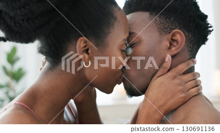 Couple, kiss and intimate in bedroom, closeup and love in passion, sex and romance by seduction. Black people, marriage and sexy on honeymoon, natural and desire in erotic or bonding for relationship 130691136