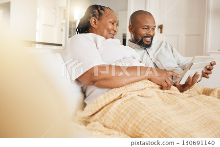 Memory, photo album and love with a black couple sitting on a sofa in the living room of their home together. Nostalgia, retirement or relax with a senior man and woman looking at photographs 130691140