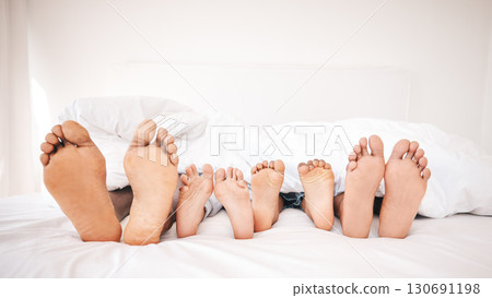 Family feet, bedroom and bed in the morning of a mother, father and young children sleeping. Mama, kids and dad foot in a house feeling relax and rest from sleep on vacation together with bonding 130691198