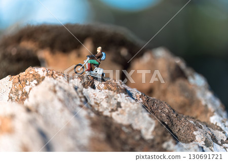 Miniature figurine of person riding motorcycle up rocky mountain 130691721