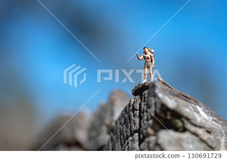Miniature hiker celebrating reaching the top of a mountain 130691729