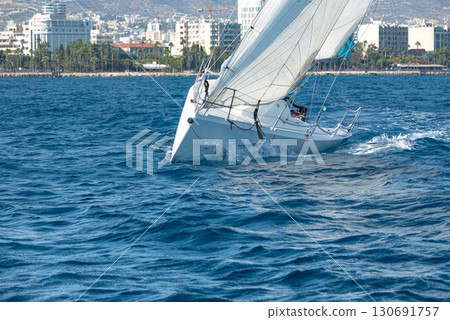 Sailboat competing in a regatta near the coastline 130691757