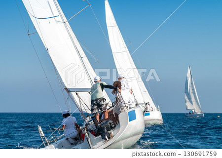 Sailors maneuvering sailboats during regatta on sunny day 130691759