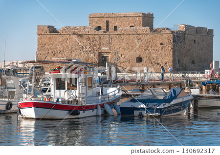 Boats moored in a bustling harbour with the historic Paphos castle in the background under a clear blue sky, capturing a blend of history and maritime life. Cyprus Boats moored in a bustling harbour with the historic Paphos castle in the background under a clear blue sky, capturing a blend of history and maritime life. Cyprus 130692317