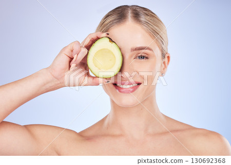 Skincare, face portrait and woman with avocado in studio isolated on a blue background. Cosmetics, fruit and happy female model holding food for omega 3, nutrition or diet, healthy skin or beauty. Skincare, face portrait and woman with avocado in studio isolated on a blue background. Cosmetics, fruit and happy female model holding food for omega 3, nutrition or diet, healthy skin or beauty. 130692368