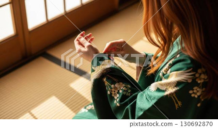 A redhead woman adjusting the sleeves of her kimono in a Japanese-style room 130692870