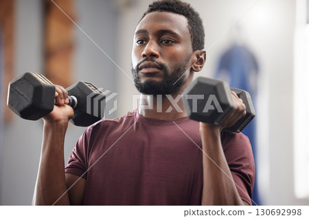 Black man, fitness and dumbbell exercise in gym for strong power, workout wellness and serious mindset. Bodybuilder, athlete and male training with weights for health, sports energy and muscle growth 130692998