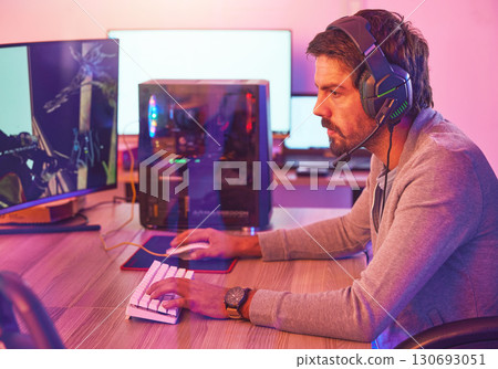 Computer gamer, man and headphones for esports, online games and virtual competition in dark room. Gaming guy, rpg player and video game on headset in neon lighting, pc technology and cyber internet 130693051