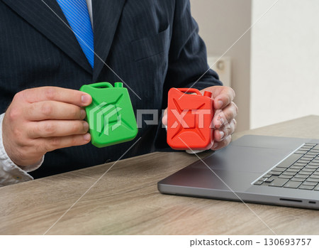 Businessman holding fossil and green fuel canisters. Concept of green transition, clean energy, environmental policy and industry standards. Used for ecology, climate change and energy markets. Businessman holding fossil and green fuel canisters. Concept of green transition, clean energy, environmental policy and industry standards. Used for ecology, climate change and energy markets. 130693757