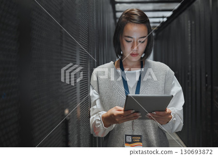 Tablet, server room and cloud computing with a programmer asian woman at work on a mainframe. Software, database and information technology with a female coder working alone on a cyber network 130693872