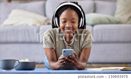 Black woman, student and phone with smile for elearning, education or entertainment by living room sofa at home. Happy African American female learner smiling on mobile smartphone lying on floor Black woman, student and phone with smile for elearning, education or entertainment by living room sofa at home. Happy African American female learner smiling on mobile smartphone lying on floor 130693978