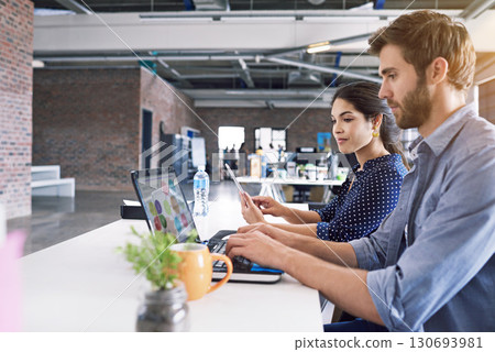 Teamwork, office and laptop, man and woman at desk with laptop at creative agency, working on project together. Leadership, partnership and happy employees or business partner at design startup. 130693981