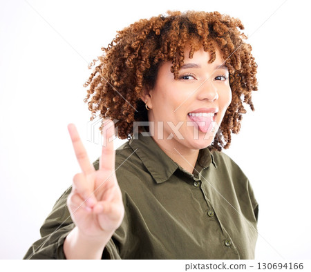 Peace, sign and portrait of black woman with tongue out excited, confident and happy isolated against a studio white background. Young, fun and hand gesture by female feeling relax and happiness Peace, sign and portrait of black woman with tongue out excited, confident and happy isolated against a studio white background. Young, fun and hand gesture by female feeling relax and happiness 130694166