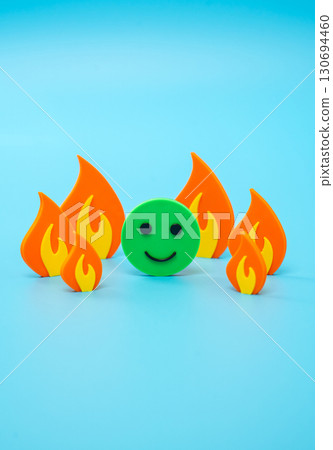 A green cheerful face is surrounded by tongues of fire flame symbolizing stress and danger. Steadfastness in difficult circumstances. Strong optimism. Stress resistance, motivation, mental strength. A green cheerful face is surrounded by tongues of fire flame symbolizing stress and danger. Steadfastness in difficult circumstances. Strong optimism. Stress resistance, motivation, mental strength. 130694460