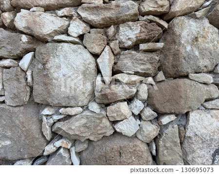 Stone wall photo, textured background. Close-up of a rustic stone wall. 130695073