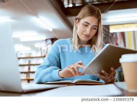 Education, university and woman in library with tablet, research and books for school project or exam. Laptop, notebook and internet, college student studying with technology and elearning on campus. 130695379