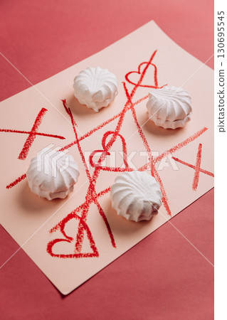Romantic tic-tac-toe game with white marshmallows and red hearts on pink background Romantic tic-tac-toe game with white marshmallows and red hearts on pink background 130695545