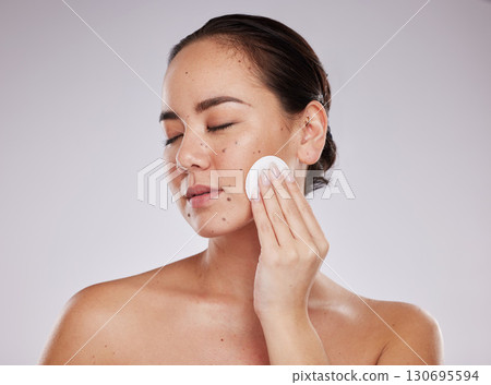 Face, skincare cotton and woman with eyes closed in studio isolated on a gray background. Makeup hygiene, beauty aesthetics and young female model with facial pad or product for cleaning cosmetics. 130695594
