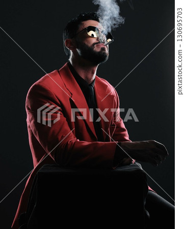 Man in red suit, smoking and fashion with style, trendy and guy on dark studio background. Mafia, male and gentleman with elegant outfit, edgy and cigarette with glamour, fancy and black backdrop Man in red suit, smoking and fashion with style, trendy and guy on dark studio background. Mafia, male and gentleman with elegant outfit, edgy and cigarette with glamour, fancy and black backdrop 130695703