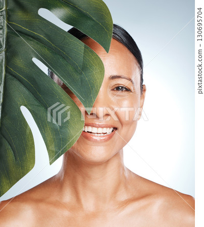 Leaf, skincare and portrait of woman in studio for skin, product and natural treatment on grey background. Plant, beauty and face of girl model smile, happy or relax for vegan, cosmetic and isolated Leaf, skincare and portrait of woman in studio for skin, product and natural treatment on grey background. Plant, beauty and face of girl model smile, happy or relax for vegan, cosmetic and isolated 130695704