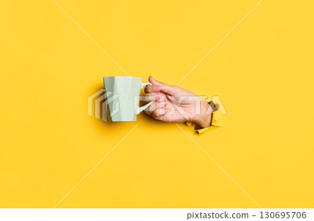 Female hand holding cup on yellow background Female hand holding cup on yellow background 130695706