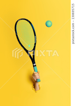 Hand holding tennis racket hitting a tennis ball 130695715