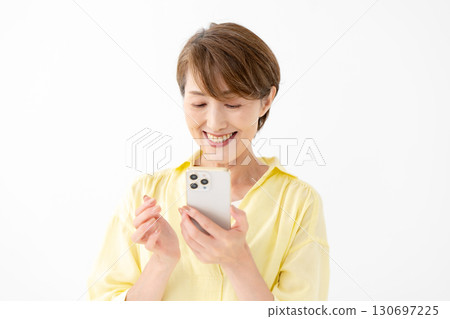 A woman operating a smartphone with a smile A woman operating a smartphone with a smile 130697225