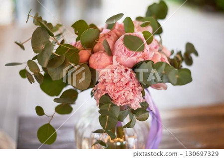 Beautiful pink peonies in a round glass vase with transparent walls. Bridal bouquet or home decoration. 130697329