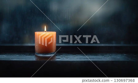 a lit orange candle in a dark window 130697368