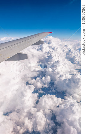View from the airplane window at a beautiful cloudy sky and the airplane wing View from the airplane window at a beautiful cloudy sky and the airplane wing 130697862