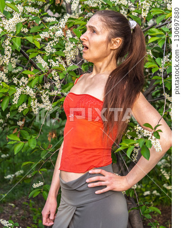 Young woman sneezes in the park against the background of a flowering tree. Allergy to pollen concept. Young woman sneezes in the park against the background of a flowering tree. Allergy to pollen concept. 130697880