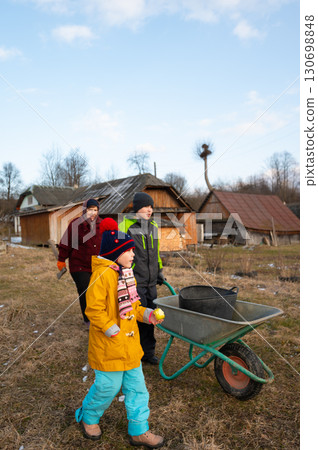 Children and adult working together in a rural setting, tending to their outdoor tasks in early spring while enjoying the fresh air and sunshine 130698848
