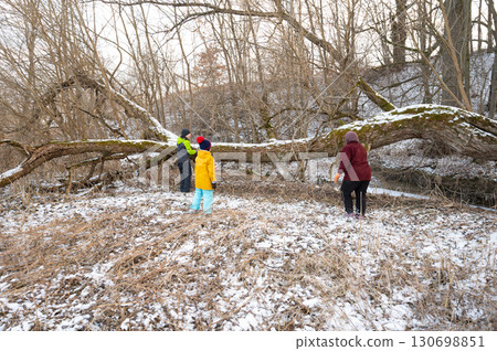 Families gather in winter to clear fallen tree from snowy creek in serene park, creating a safe space for outdoor play and exploration amidst nature Families gather in winter to clear fallen tree from snowy creek in serene park, creating a safe space for outdoor play and exploration amidst nature 130698851