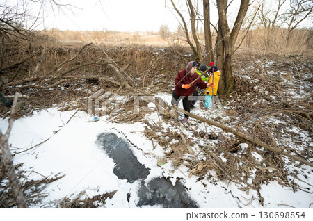 Winter exploration in a snowy landscape with children discovering nature near a frozen creek in a quiet wooded area Winter exploration in a snowy landscape with children discovering nature near a frozen creek in a quiet wooded area 130698854