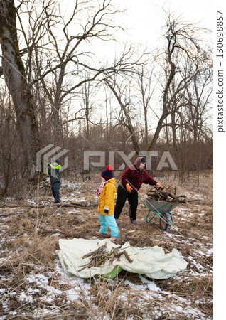 Community members gather in a serene landscape, engaging in productive work while collecting firewood on a chilly afternoon in the early spring 130698857