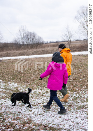 Enjoying a winter stroll through a frosty landscape with a playful dog while dressed warmly against the cold weather and cozying up to nature's beauty Enjoying a winter stroll through a frosty landscape with a playful dog while dressed warmly against the cold weather and cozying up to nature's beauty 130699247