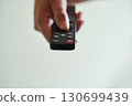Hand holding a remote control indoors 130699439