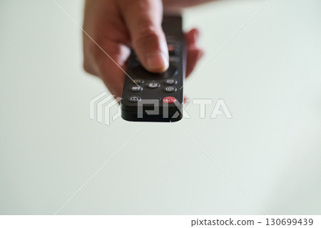 Hand holding a remote control indoors 130699439