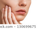 sad female holds sore cheek on white isolated background. Severe ache toothache. Problems and pain in teeth and gums. Dentistry and dental clinic 130699675