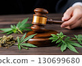 judge's gavel in the male hand and marijuana leaves in the courtroom. Concept of legalizing and decriminalizing weed and drugs 130699680