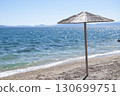 An umbrella on the empty beach. A seashore background with an umbrella. A seascape frame with copy space. Travelling and tourism background. 130699751
