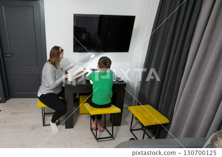 Focused study session in a modern living room with a student and a mentor working together on academic tasks in the morning light 130700125