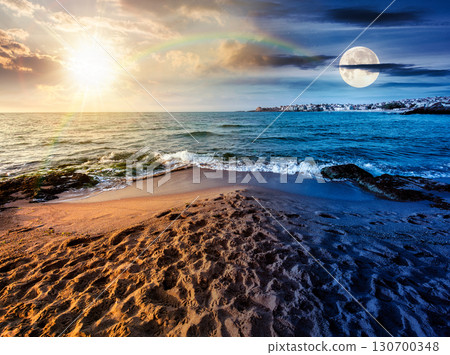 sunrise on a sandy town beach on equinox season. day and night time change concept. beautiful and warm weather on the shores of black sea. coast with sun and moon at twilight sunrise on a sandy town beach on equinox season. day and night time change concept. beautiful and warm weather on the shores of black sea. coast with sun and moon at twilight 130700348