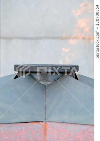 Eternal flame at the memorial with burning flame against the background of the city square. Close-up of flames. 130700554
