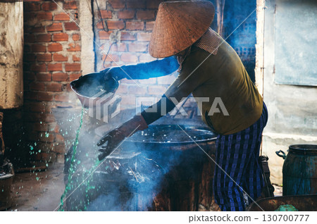 Vietnamese female worker puts out a fire in furnace in workshop at a factory in village. Asian woman does dirty hard men's work in a factory in Asia 130700777
