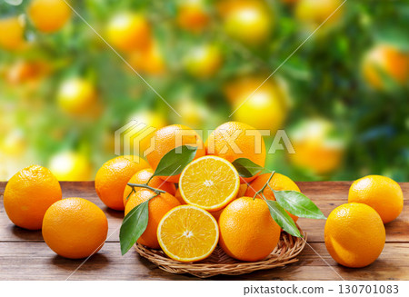 fresh orange fruits with leaves on wooden table on garden background 130701083